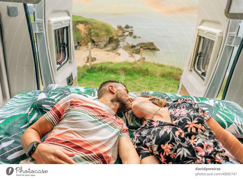 Küssendes Paar auf dem Bett ihres Wohnmobils liegend jung Kuss Lügen Landschaft Ausflug Küste offen Tür MEER Meer romantisch Freiheit mobiles Zuhause Lächeln