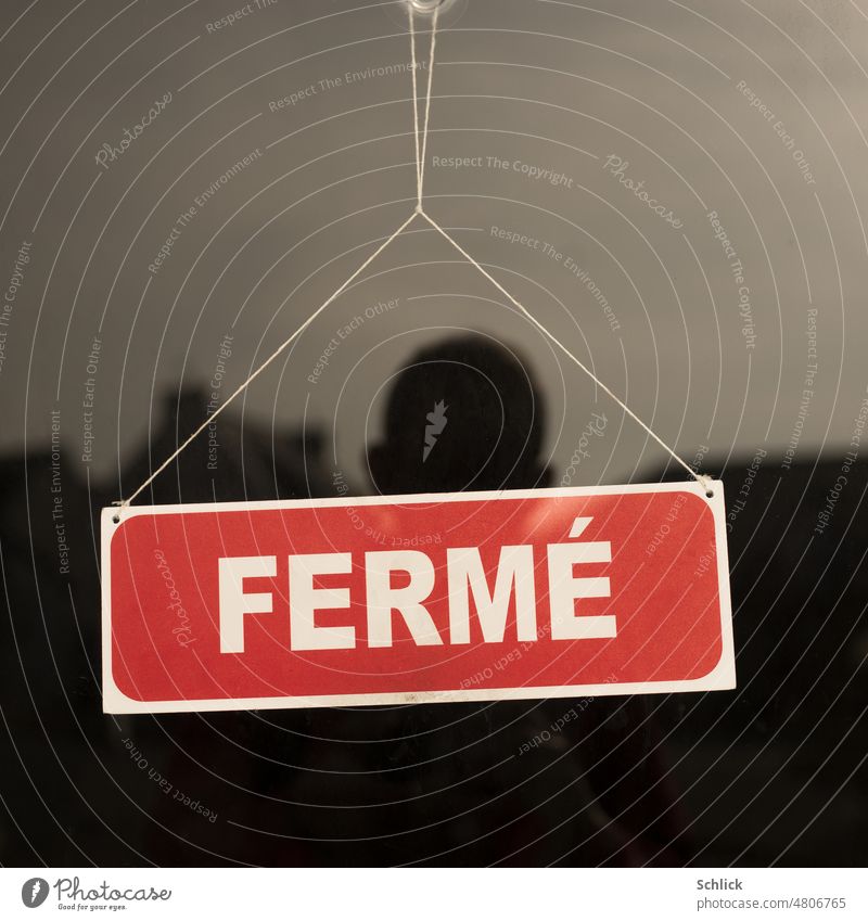Selfie als Spiegelung im Schaufenster und Schild FERME anonym Fenster Glas Text FERMÈ Kopf Ohren Haare Horizont Himmel entsättigt rot weiß Haus