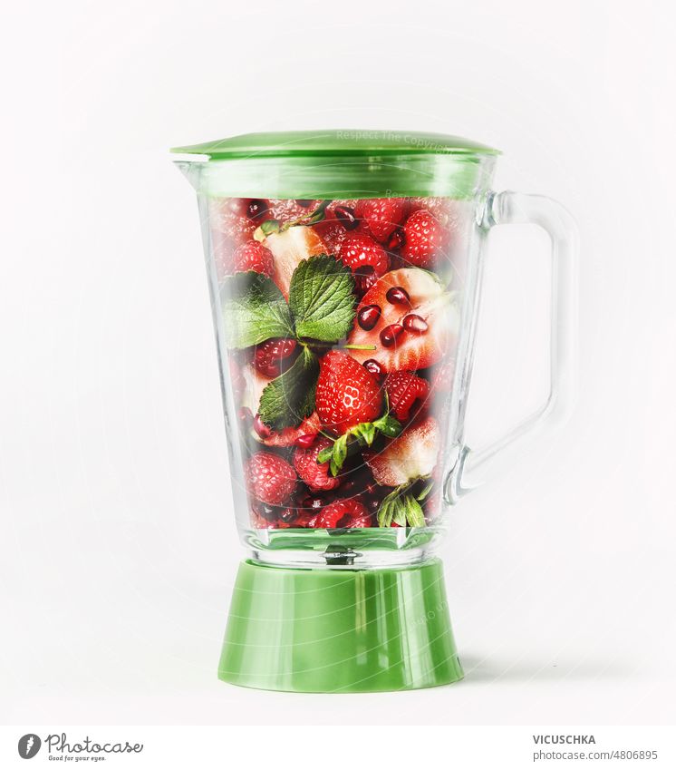 Grüner Mixer mit roten Früchten: Erdbeeren, Himbeeren, Minzblätter und Granatapfelkerne. Mischer Smoothie erdbeeren erfrischend Vorbereitung Gesundheit Zutaten