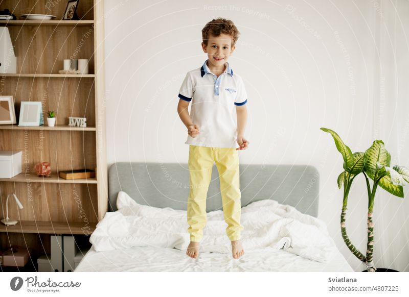 Ein kleiner Junge springt auf sein Bett im Schlafzimmer und lacht. springend jung Kind heimwärts Kaukasier Glück Spaß spielen Kindheit aktiv Person Raum Spielen