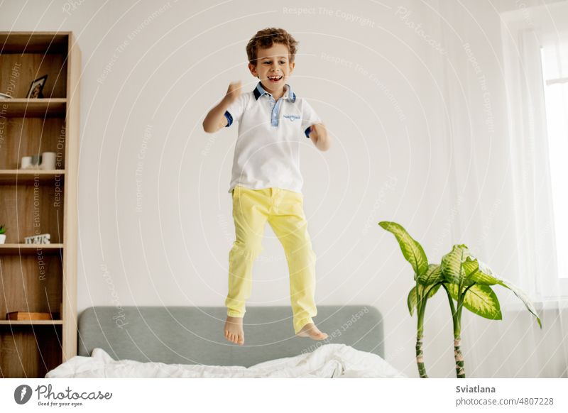 Ein kleiner Junge springt auf sein Bett im Schlafzimmer und lacht. springend jung Kind heimwärts Kaukasier Glück Spaß spielen Kindheit aktiv Person Raum Spielen