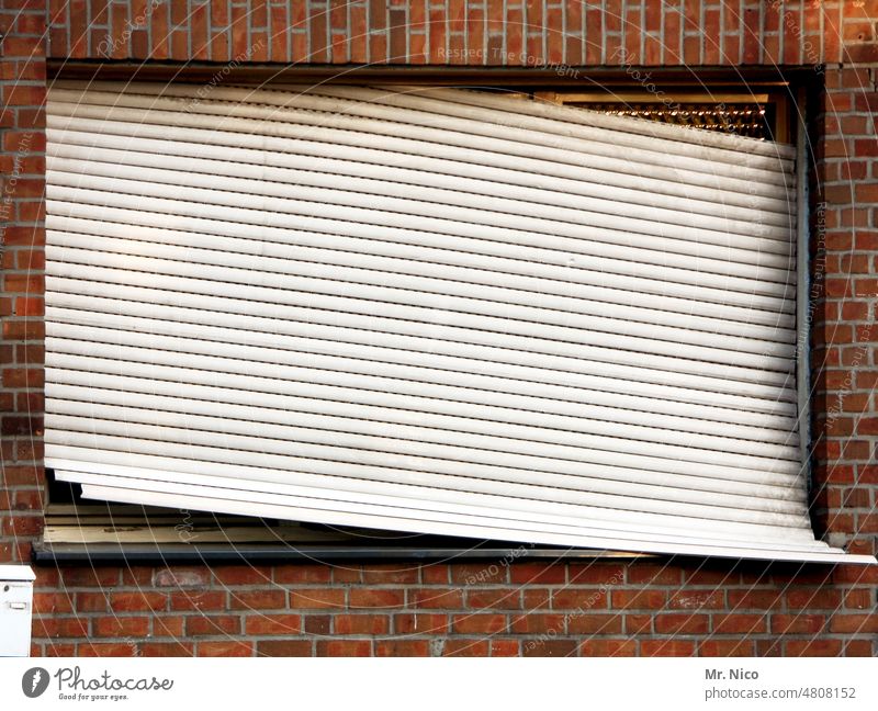 schräg Haus Wohnung Häusliches Leben Fenster Rollladen Renovieren kaputt geschlossen Rolladen schief Schieflage Gebäude trist krumm und schief Wetterschutz