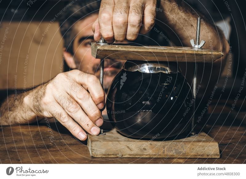 Männlicher Handwerker beim Einstellen der Tasse in einer Holzpresse Kunsthandwerker ausrichten Presse Werkstatt Hobelbank Arbeit ernst handgefertigt männlich