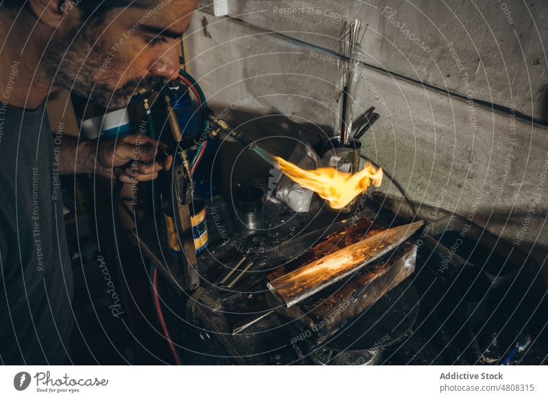 Männlicher Silberschmied bei der Herstellung einer Silberscheide Mann Brandwunde Feuer Scheide Handwerk Metallbearbeitung Werkstatt Fackel männlich reif