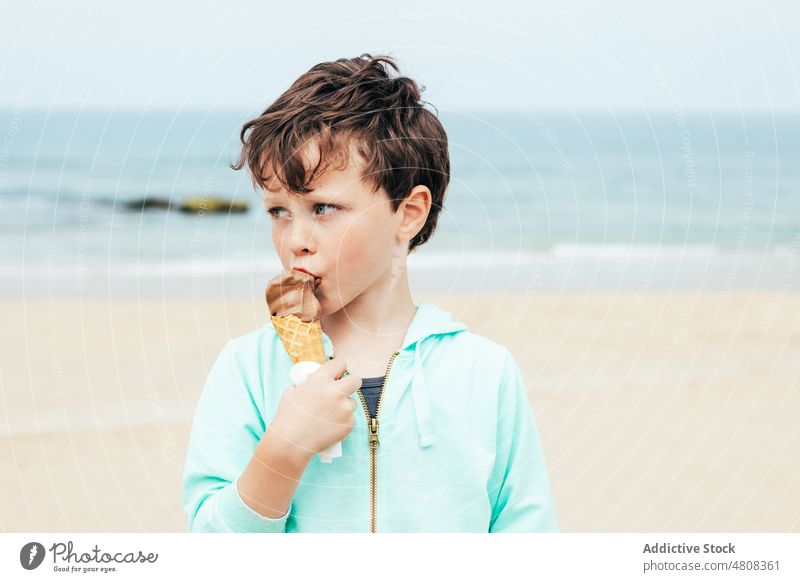 Junge isst Schokoladeneis am Strand Speiseeis lutschen Lächeln Sommer Wochenende Porträt süß Kind Dessert niedlich lecker bezaubernd Kindheit Seeküste Wasser