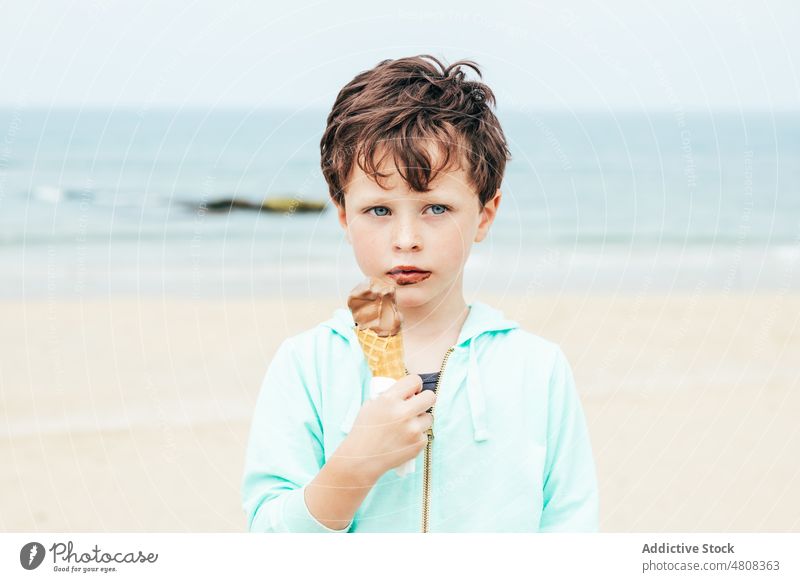 Junge isst Schokoladeneis am Strand Speiseeis lutschen Lächeln Sommer Wochenende Porträt süß Kind Dessert niedlich lecker bezaubernd Kindheit Seeküste Wasser