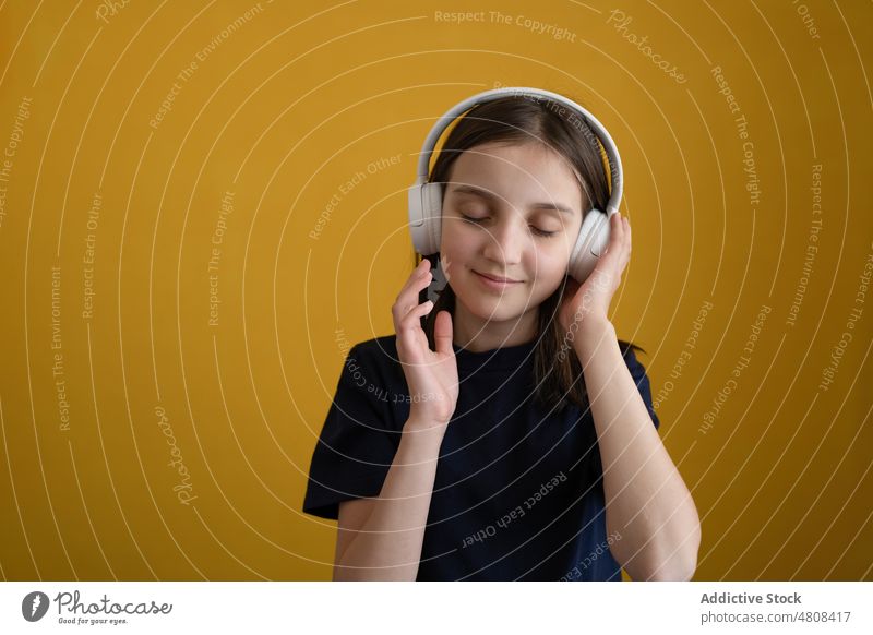 Zufriedenes Kind mit geschlossenen Augen, das mit Kopfhörern Musik hört Mädchen zuhören Augen geschlossen genießen Gesang Freude Klang Porträt meloman Lächeln