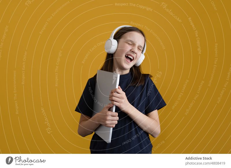 Glückliches Mädchen mit Kopfhörern singt, während sie im Studio Lieder hört zuhören Musik singen Augen geschlossen expressiv Gesang laut Teenager meloman