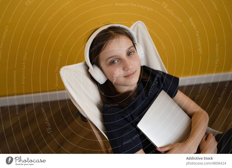 Ruhiges Mädchen sitzt auf einem Stuhl und hört ein Lied zuhören Musik sich[Akk] entspannen Kälte genießen Gesang Kopfhörer Windstille meloman Melodie Kind