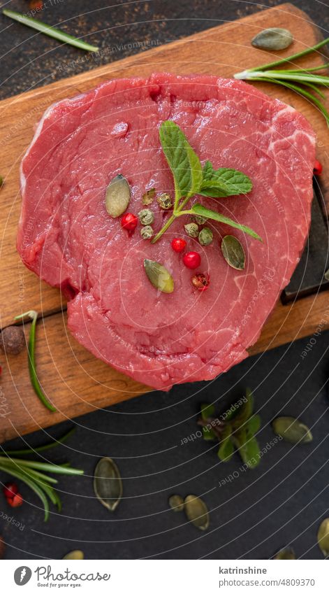 Rohes Rinderfiletsteak mit Kräutern und Gewürzen auf Holzbrett auf dunklem Tisch Draufsicht Fleisch Filet Lebensmittel roh Steak rot Rindfleisch frisch mignons