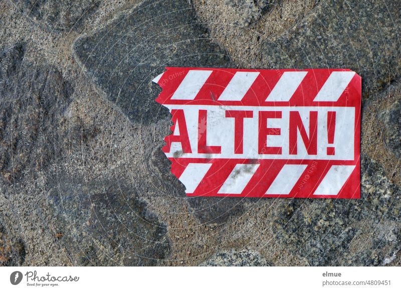 Reste eines auffälligen, rot markierten Schildes mit der Aufschrift  - ALTEN ! - auf dem grauen Straßenpflaster / Abstand halten Alte Coronavirus