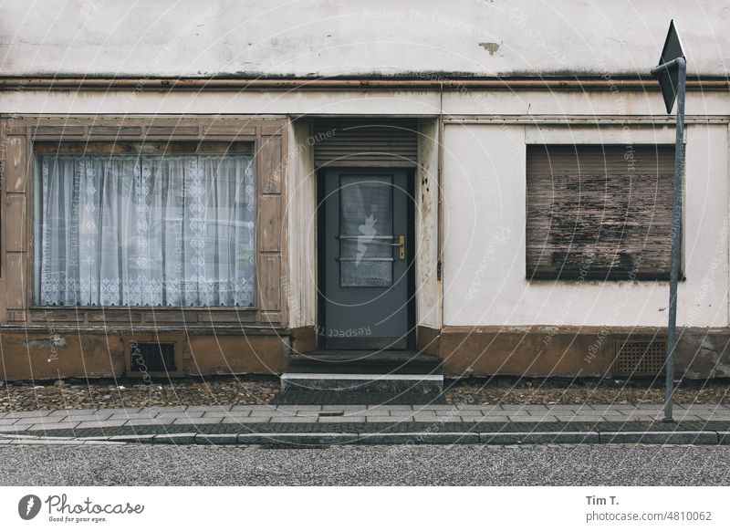 eine Ladenwohnung in der Lausitz Dorf Ladengeschäft Brandenburg Gardine Eingang Außenaufnahme Tag Menschenleer Farbfoto geschlossen Fassade Wand Tür Haus