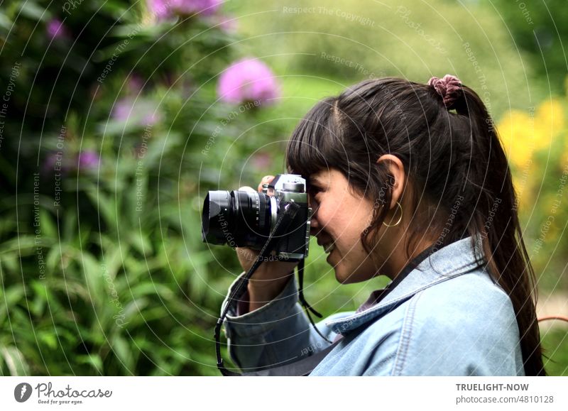 [Hansa BER 2022] Fröhliche junge Frau und Fotografin erfreut sich mit ihrer Kamera an der Blumenpracht im Mai Portrait Profil Kopf Schulter Gesicht Freude