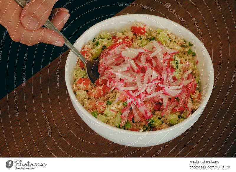 Eine Schüssel veganen Couscous-Salat mit frischem, geraspeltem Rettich anrühren Salatbeilage Vegane Ernährung Veganismus Gesunde Ernährung