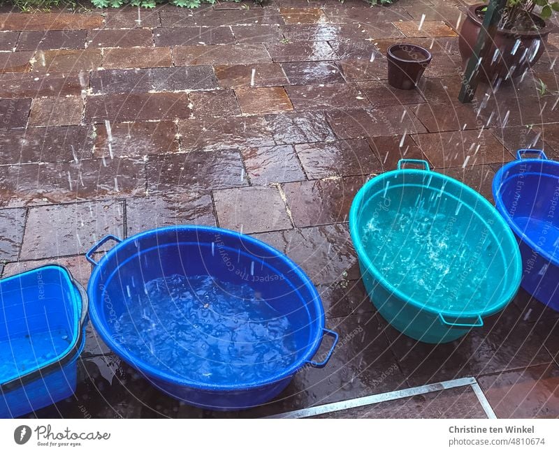 Starkregen, das Wasser fällt aus der überlaufenden Regenrinne direkt in die bereitgestellten Wäschewannen nass Regenwasser sammeln Kellergitter Terrasse