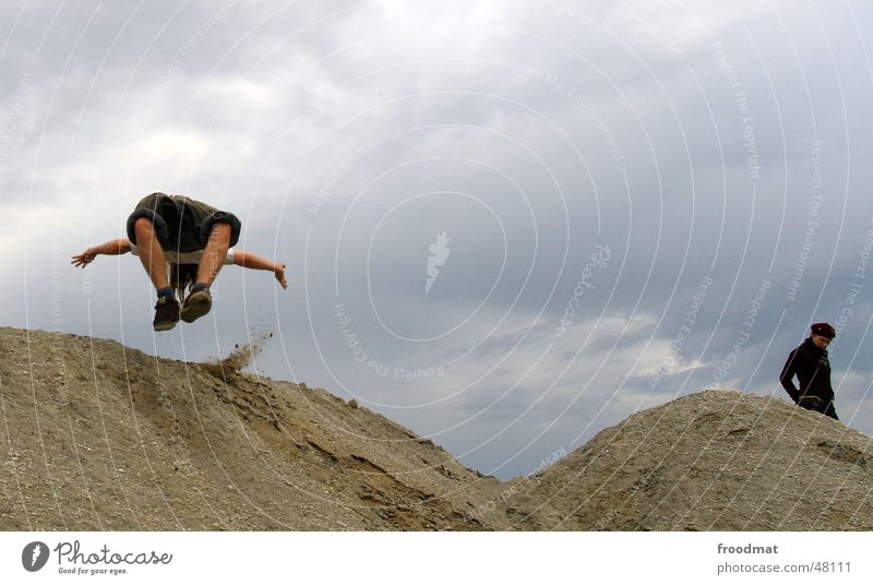 Salto Mann Frau springen Aktion grau schlechtes Wetter man woman Bergbau Sand Wüste Regen Wolken fliegen Bewegung Dynamik Konstruktion