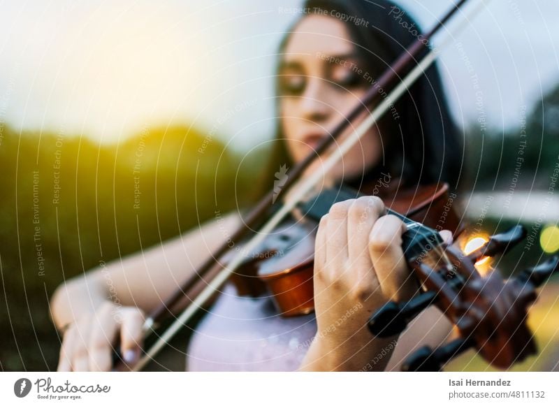 Nahaufnahme der Hände einer Geige spielenden Frau im Freien, Ein Mädchen mit ihrer Geige spielt eine Melodie im Freien, Gesicht einer Geige spielenden Frau, Porträt eines Geige spielenden Mädchens