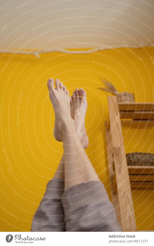Crop-Frau mit hochgelegten Beinen heimwärts Bein angehoben Morgen Wand Barfuß Energie Zen Achtsamkeit Stressabbau Wellness Sportbekleidung Vitalität