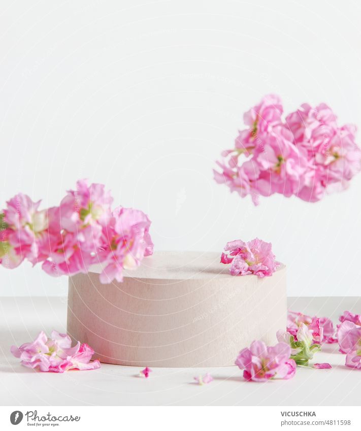 Moderne florale Produktpräsentation mit Podium, fliegenden rosa Blumen auf weißem Hintergrund. modern geblümt weißer Hintergrund Szenenaufbau Vitrine