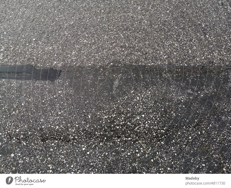 Alter grauer Asphalt einer Straße auf dem Deich am Hafen von Norddeich bei Regen an der Nordsee in Ostfriesland bei Norden in Niedersachsen wandern Landleben