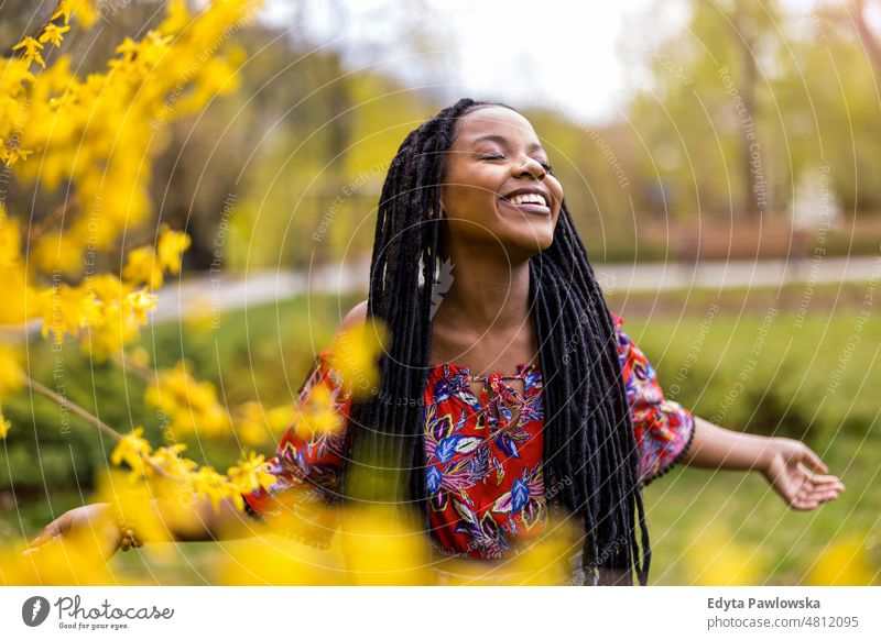 Schöne junge Frau genießt den Frühling im Park cool sorgenfrei selbstbewusst Tag Jahrtausende Rastalocken genießen authentisch positiv echte Menschen freudig