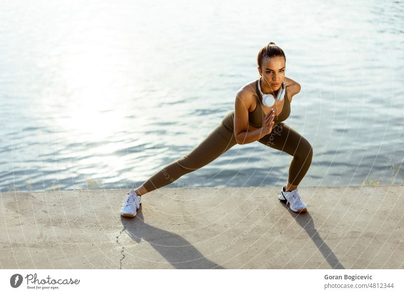 Junge Frau in Sportkleidung beim Stretching an einer Flusspromenade aktiv sportlich schön Kaukasier Energie Übung passen Fitness Flexibilität Gesundheit Jogger
