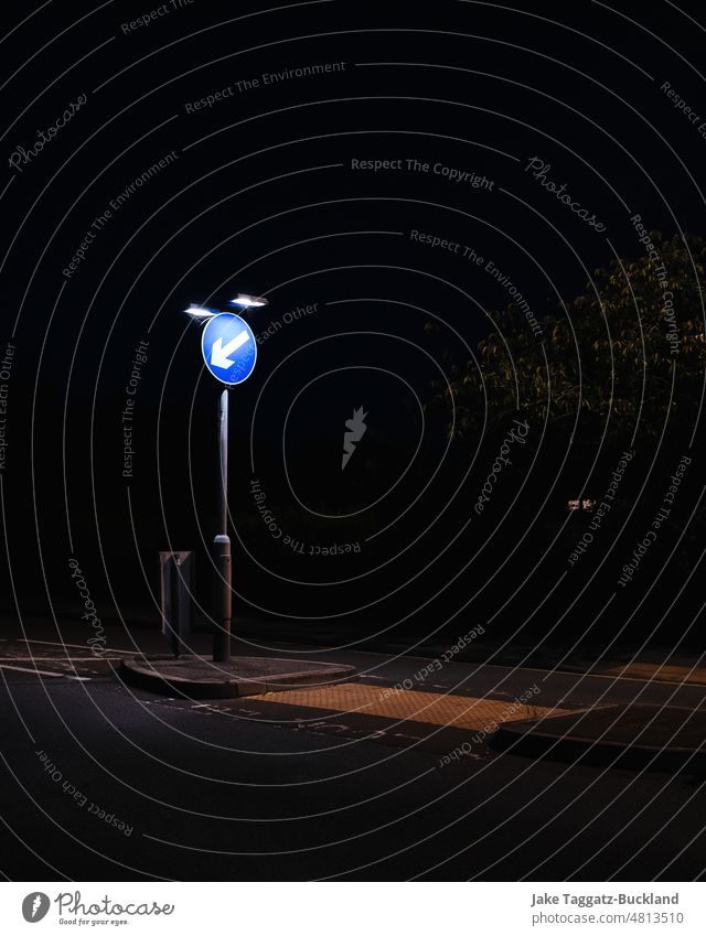 Vertikale Aufnahme eines britischen "Keep Left"-Verkehrsschilds bei Nacht mit kontrastreicher starker künstlicher Beleuchtung Briten reisen links Seife abstrakt