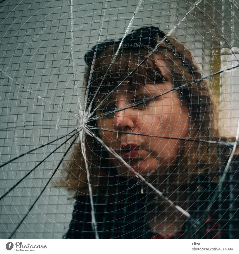 [hansa BER 2022] Frau begutachtet eine gesprungene Fensterscheibe kaputt Glas zerbrochen Glasscheibe Vandalismus gebrochen Zerbrochenes Fenster Sprung Schaden