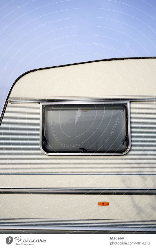 Fenster mit Sonnenschutz eines alten Wohnwagen in Pastelltönen und Naturfarben für Camping und Vanlife im Sonnenschein auf dem Campingplatz am Segelflugplatz in Oerlinghausen bei Bielefeld am Hermannsweg im Teutoburger Wald in Ostwestfalen-Lippe