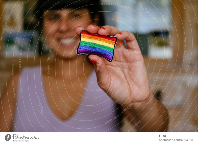Lächelnde Frau streckt eine Regenbogenflagge in die Kamera Pride Toleranz Vielfalt Gleichstellung Freiheit lgbtq lgbtq+ Stolz Regenbogenfahne lila Symbol Liebe