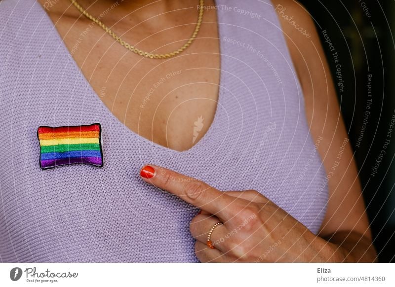 Frau zeigt mit dem Finger auf eine Regenbogenflagge, die sie an ihr Top geheftet hat Pride Toleranz Vielfalt Gleichstellung Freiheit lgbtq lgbtq+ Stolz