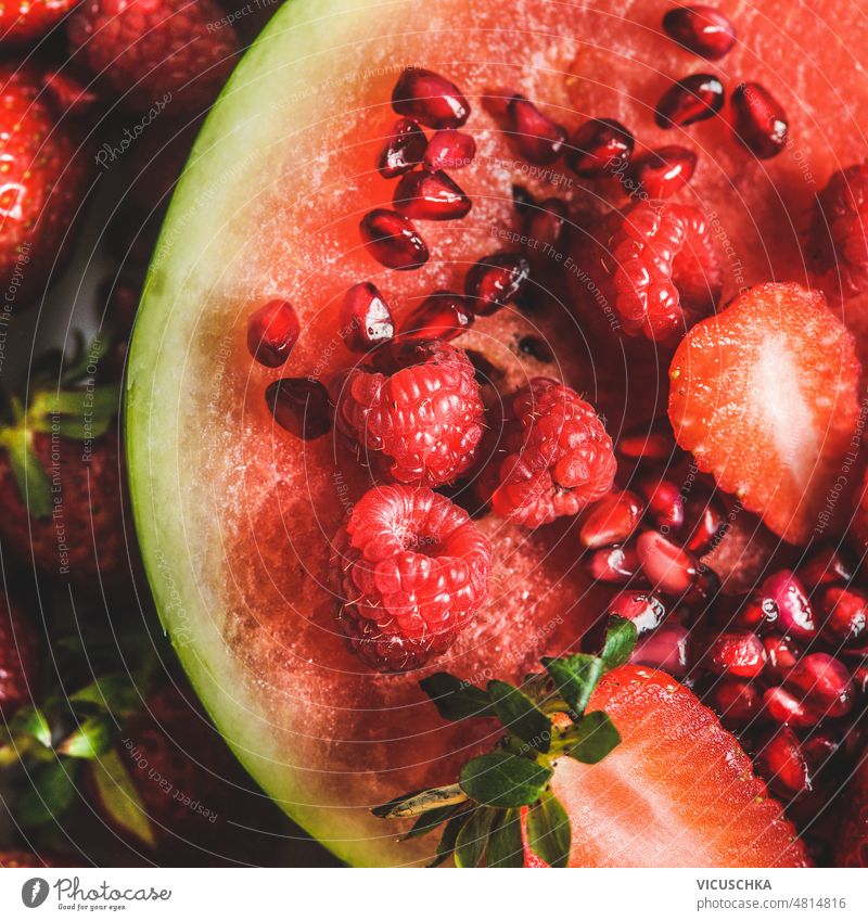 Nahaufnahme von roten Früchten auf einer aufgeschnittenen Wassermelone: Erdbeeren, Himbeeren und Granatapfelkerne. abschließen erdbeeren lecker süß Dessert