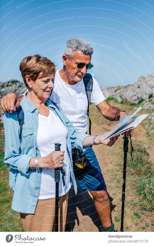 Älteres Paar mit Stöcken beim Trekking mit Blick auf die Karte Senior heiter umarmend Landkarte Lächeln Mann Frau Ausflug Person Lifestyle Urlaub Wanderer älter