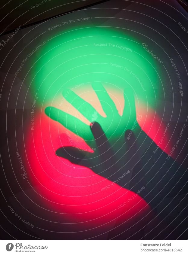 Zwei Schatten Hände in rotem und grünen Lichtkreis. Zentralperspektive Lichterscheinung Kunstlicht Hintergrund neutral Muster abstrakt Experiment Innenaufnahme
