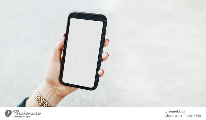 Weibliche Hand hält Smartphone Mockup mit fester weißer Farbe leeren leeren Bildschirm auf flachen Hintergrund. Person mit Technologie. Mobiltelefon mit Kopie Raum rechts