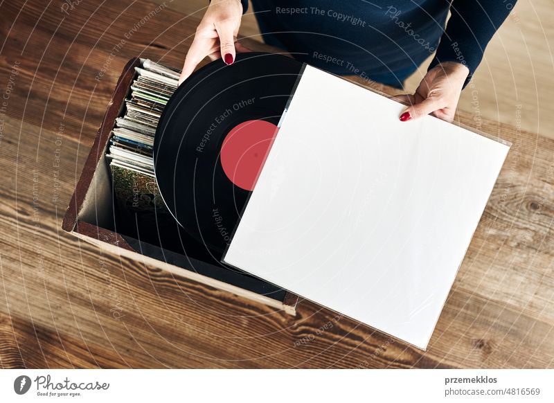 Abspielen von Vinyl-Schallplatten. Hören von Musik aus Vinyl-Schallplattenspieler. Retro- und Vintage-Musikstil. Frau hält analoges LP-Album. Musik Leidenschaft