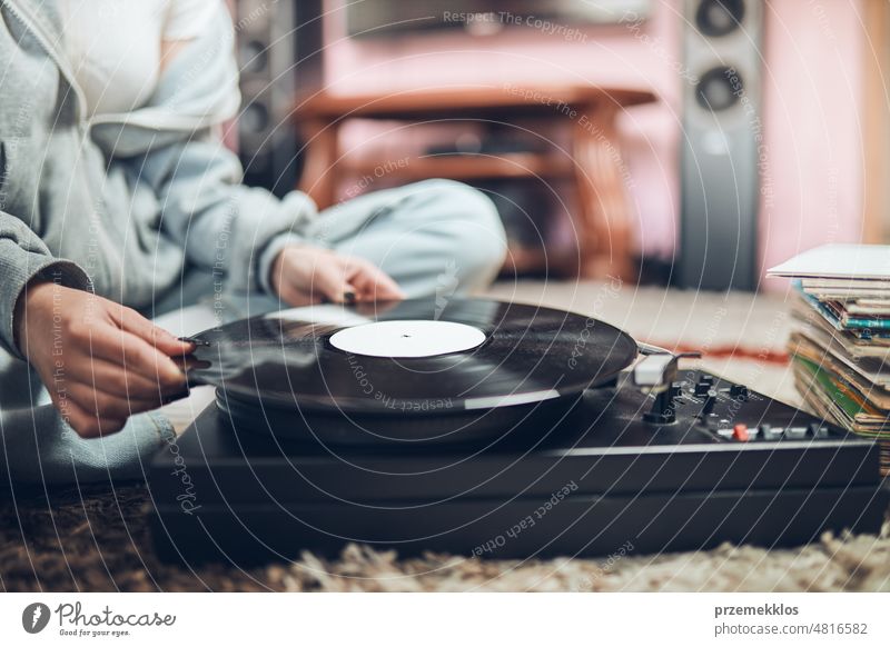 Junge Frau hört Musik von einem Schallplattenspieler. Retro und Vintage-Musik-Stil. Mädchen hält analoge Schallplatte Album. Frau genießt Musik aus alter Plattensammlung