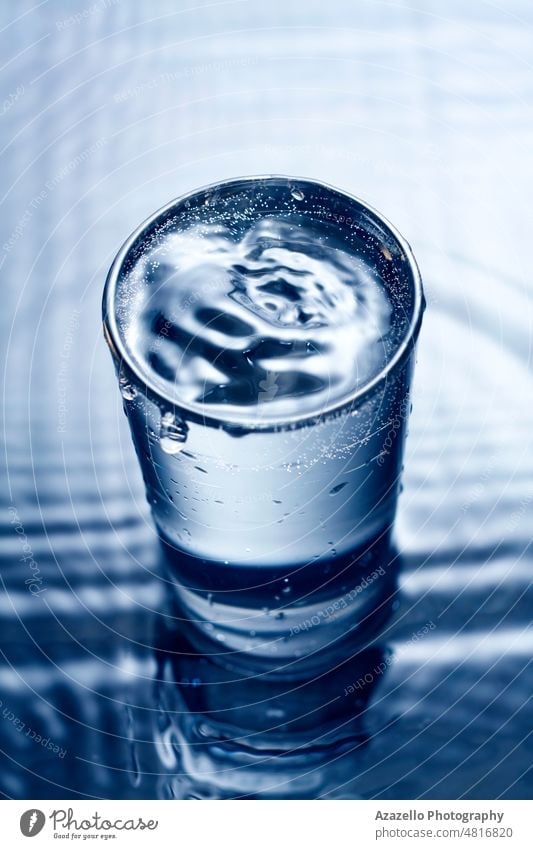 Blaues monochromes Bild von plätscherndem Wasser in einem Glas. blau platschen gespritzt kräuselt Unschärfe verschwommen winken Oberfläche Tröpfchen trinken