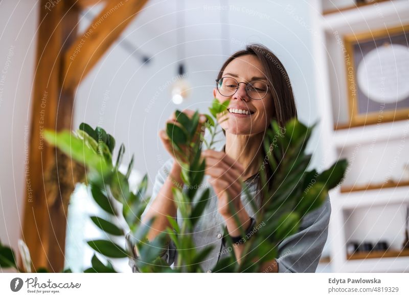 Junge Frau, die sich um ihre Zimmerpflanzen kümmert eingetopft Pflege grün Natur Blätter Frische Hobby wachsen Blumentopf Gartenarbeit frisch Blumenhändler