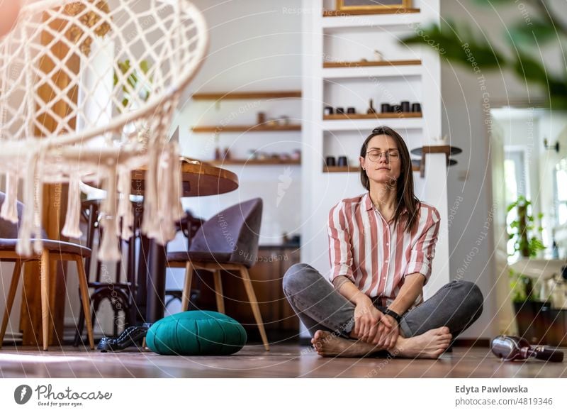 Entspannte junge Frau, die zu Hause auf dem Boden sitzt häusliches Leben Selbstvertrauen im Innenbereich heimwärts Menschen Erwachsener lässig Kaukasier