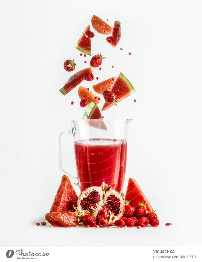 Roter Smoothie im Mixer mit fallenden Zutaten: Grapefruit, Wassermelone, Granatapfel, Erdbeeren und Himbeeren. rot Mischer erdbeeren Gesundheit