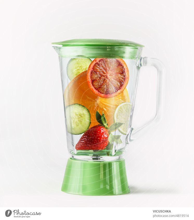 Mixer mit verschiedenen Smoothie-Zutaten auf weißem Hintergrund. Gesundes erfrischendes Getränk Vorbereitung Mischer weißer Hintergrund Salatgurke orange
