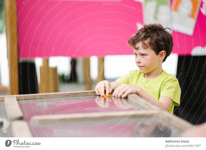 Entzückendes Kind am Tisch im Unterhaltungsclub Airhockey Spiel Konzentration unterhalten Junge spielen Vergnügen Kindheit Zentrum Porträt bezaubernd Fokus