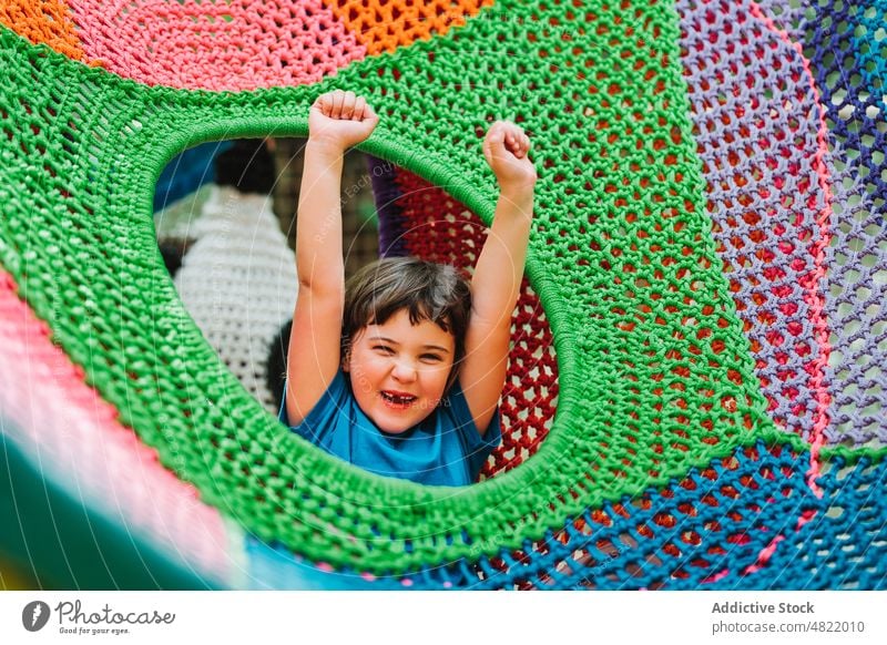 Glückliches niedliches Kind liegt in einer bunten Hängematte Mädchen sich[Akk] entspannen Park genießen Lächeln gestrickt sorgenfrei farbenfroh Porträt