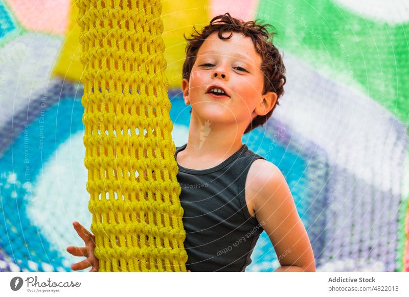 Inhalt kleines Kind spielt auf gestricktem Trampolin auf Spielplatz spielen Lächeln Glück heiter unterhalten Junge Kindheit Freude Porträt Zentrum positiv