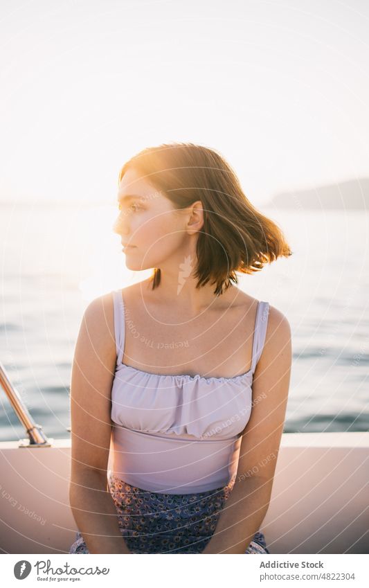 Ruhige junge Frau bewundert die Natur, während sie auf einem Segelboot sitzt MEER Jacht bewundern Feiertag Kreuzfahrt Sommer Urlaub Porträt sitzen trendy Stil