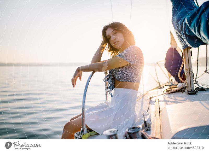 Stilvolle weibliche Touristin, die sich auf einer Jacht ausruht und den Sonnenuntergang über dem Meer bewundert Frau bewundern MEER Segelboot Reisender Urlaub