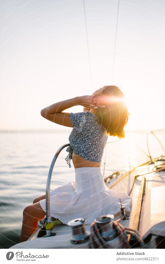 Stilvolle weibliche Touristin, die sich auf einer Jacht ausruht und den Sonnenuntergang über dem Meer bewundert Frau bewundern MEER Segelboot Reisender Urlaub
