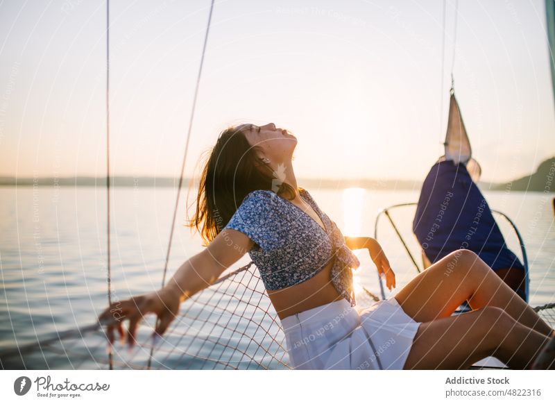 Stilvolle weibliche Touristin, die sich mit geschlossenen Augen auf einer Yacht ausruht Frau MEER Segelboot Reisender Sonnenuntergang Urlaub Kreuzfahrt Feiertag