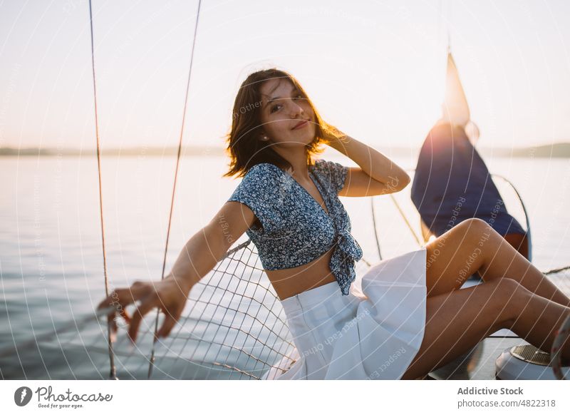 Stilvolle Touristin, die auf einer Yacht ruht und in die Kamera schaut Frau bewundern MEER Segelboot Reisender Sonnenuntergang Urlaub Kreuzfahrt Feiertag